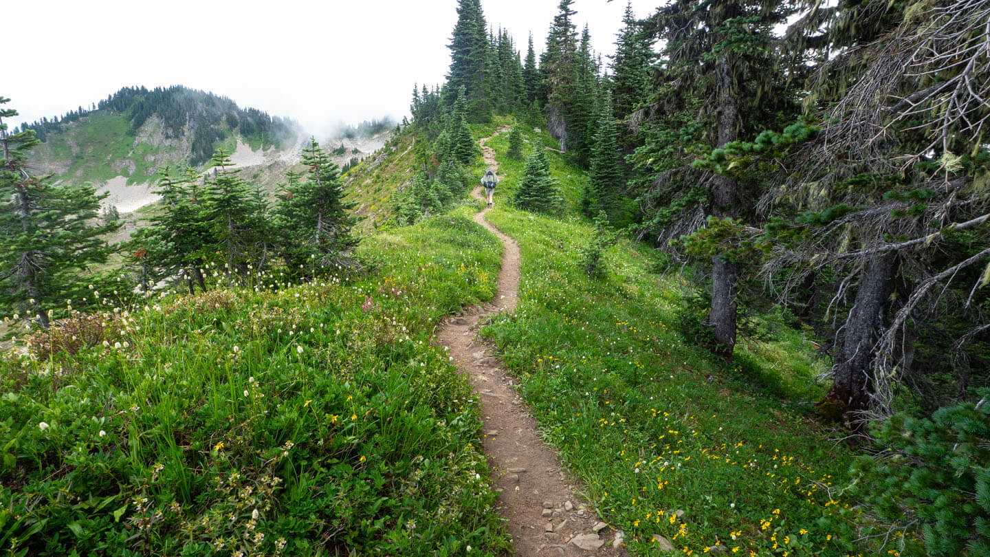 Trail with backpacker, walking on ridge.