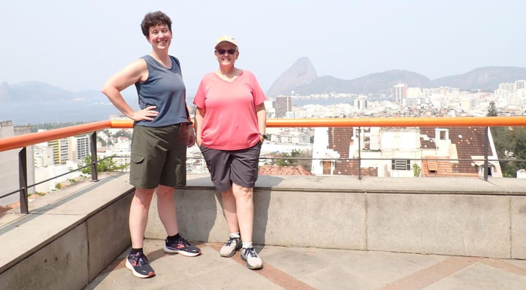 Allison and Sheila stand in corner overlooking city.